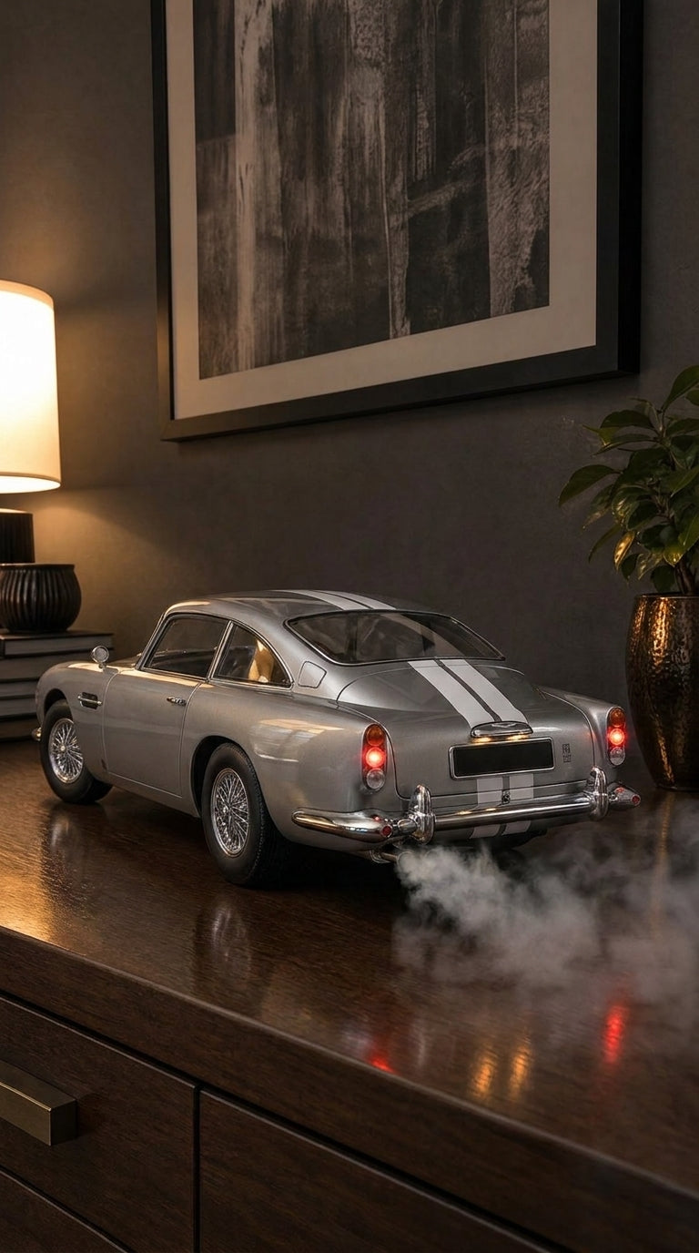 Silver Aston Martin DB5 model with chrome overriders and wire wheels, smoke from the twin exhaust