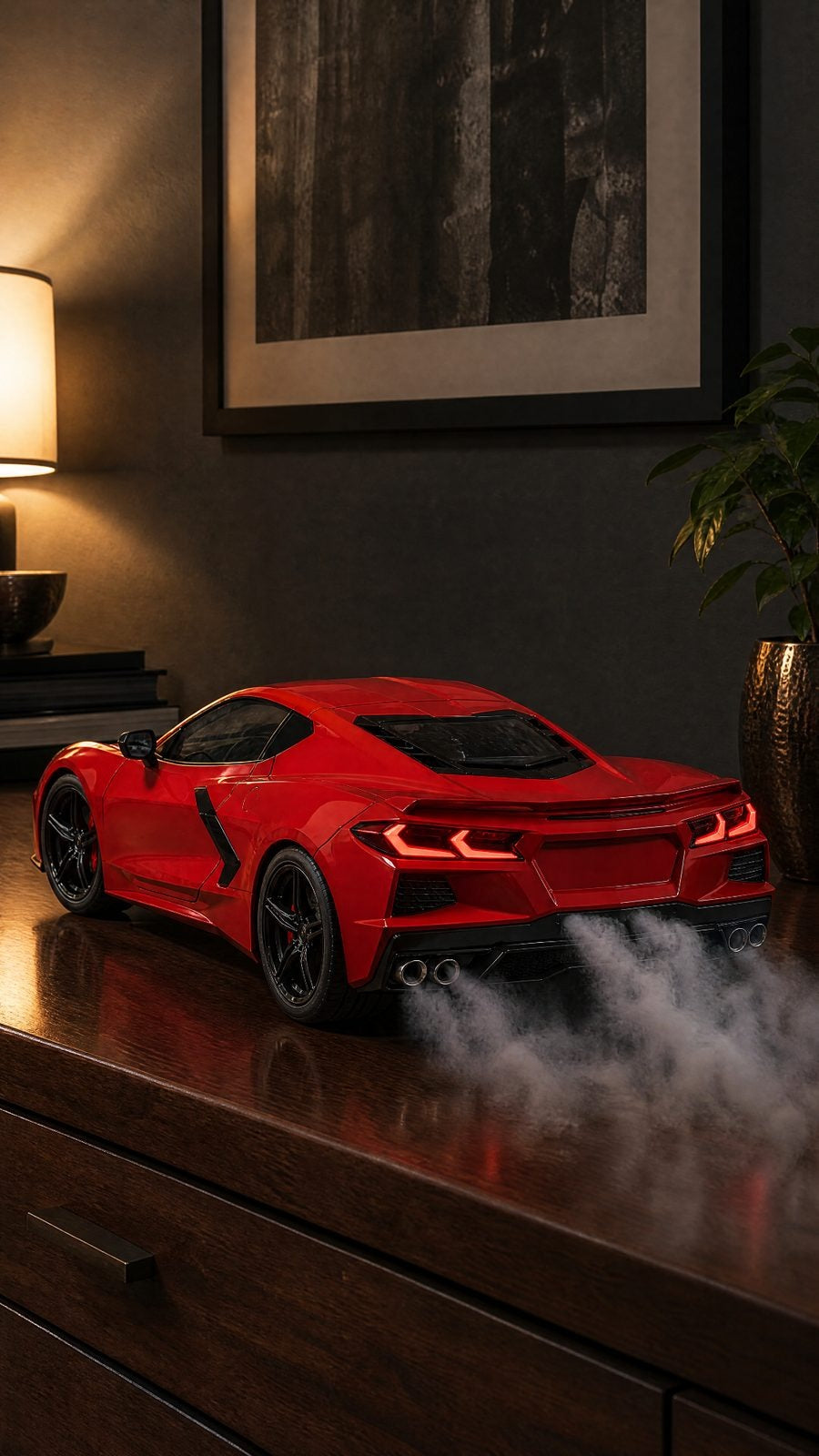Red Corvette C8 die-cast model on a wooden dresser, smoke rolling from its quad exhaust, LED tail lights on